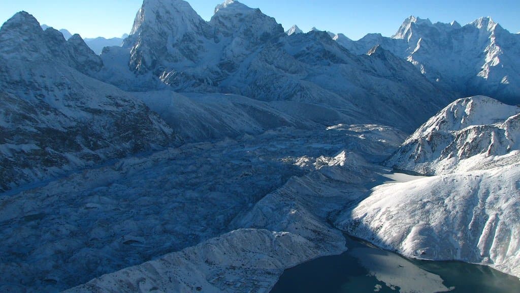 A large Himalayan glacier below snow-capped peaks in Nepal at sunrise