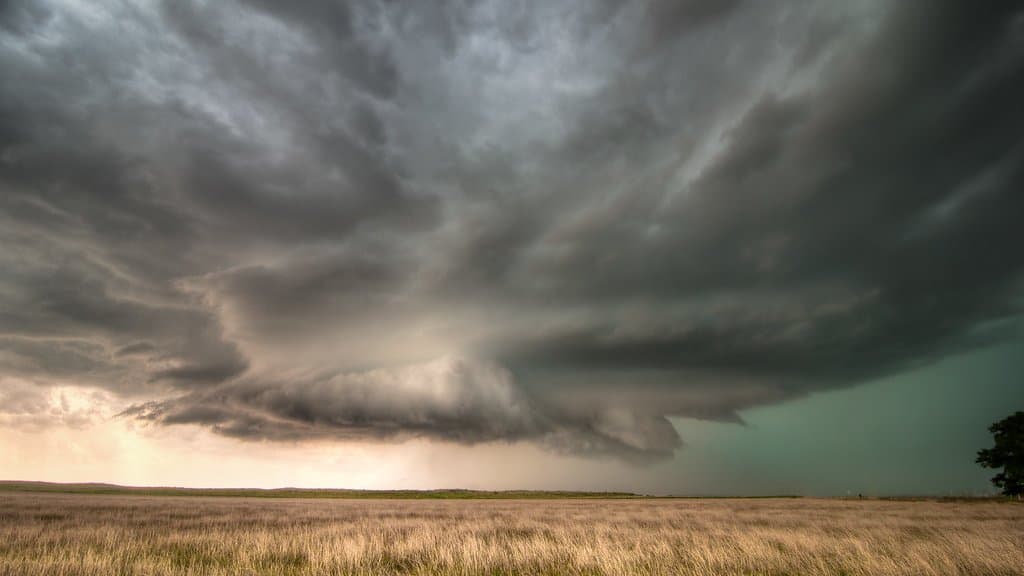 A large supercell thunderstorm with a dark rotating base over open country