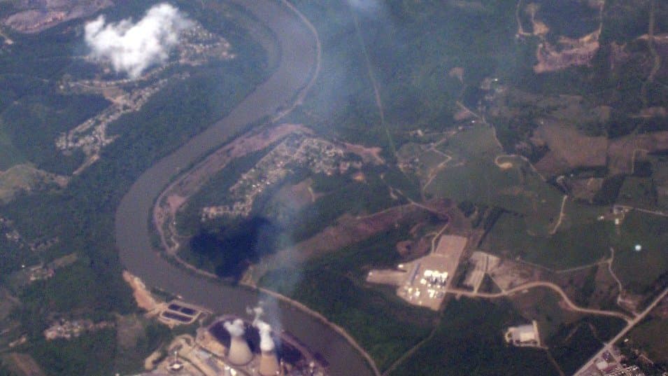 A coal-fired power plant with cooling towers releasing plumes of steam and emissions.