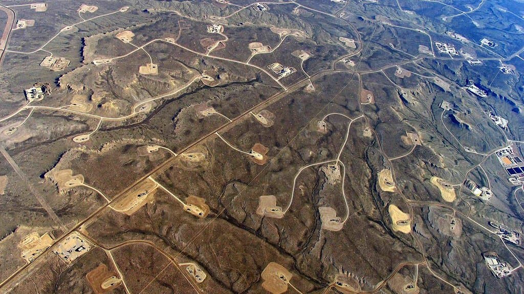 An industrial hydraulic-fracturing operation with drilling equipment and tanks at a well site.