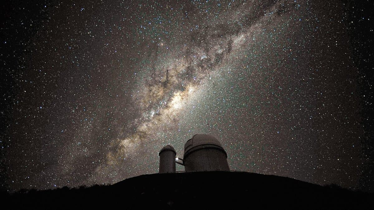 The dense star clouds and dust lanes of the Milky Way's central bulge rising above an observatory dome.