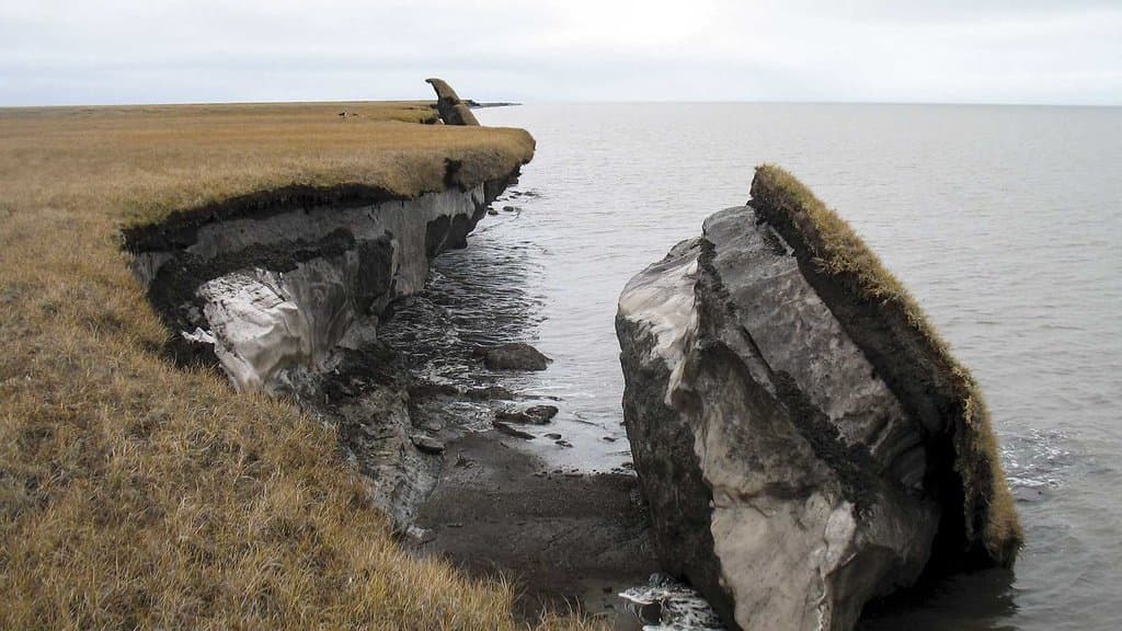 An eroding Arctic coastal bluff of frozen ground collapsing into the sea