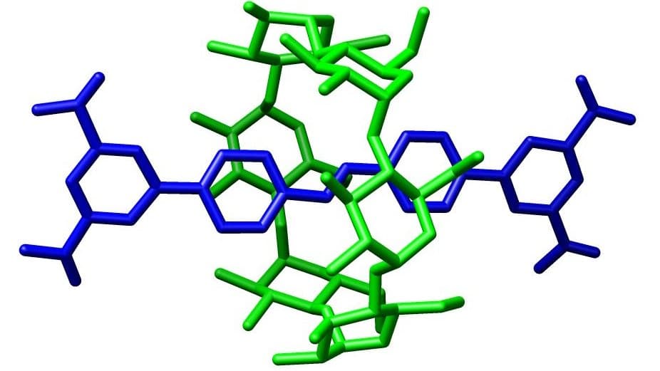 Stick-model molecular structure on a white background: a blue rod-like molecule runs horizontally across the frame with a branched ring at each end, while a separate green ring-shaped molecule loops around its middle, encircling the blue chain without being joined to it.