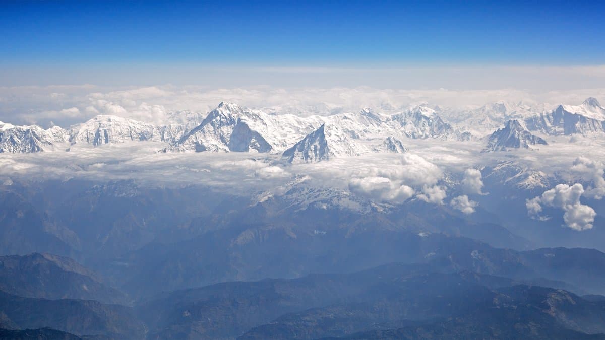Aerial view of the snow-covered Annapurna massif in the Nepal Himalaya, glaciated peaks and steep ridges rising above cloud.