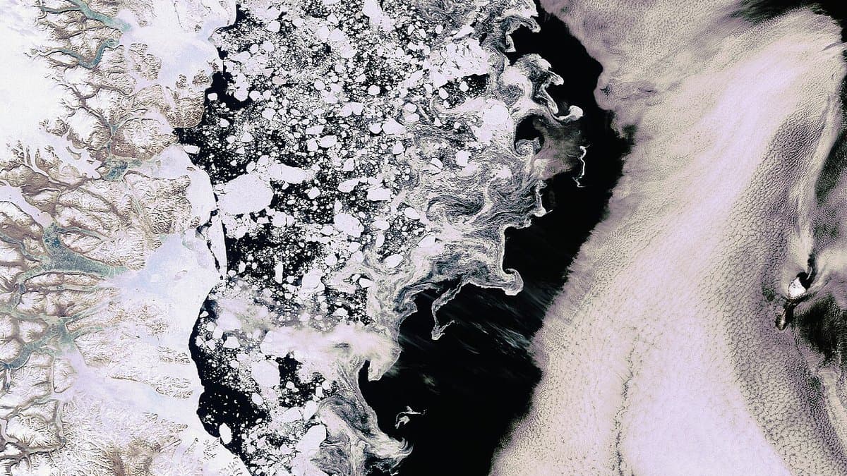 Satellite view of broken white sea ice drawn into swirls and streaks across dark open ocean