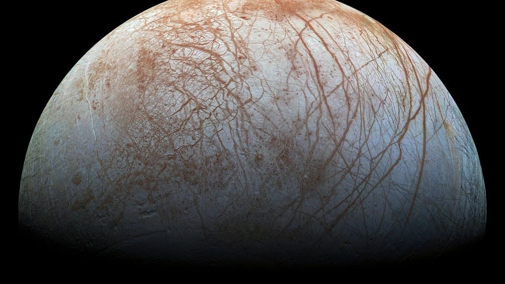 Jupiter's moon Europa, a pale blue-white icy globe criss-crossed by long reddish-brown cracks