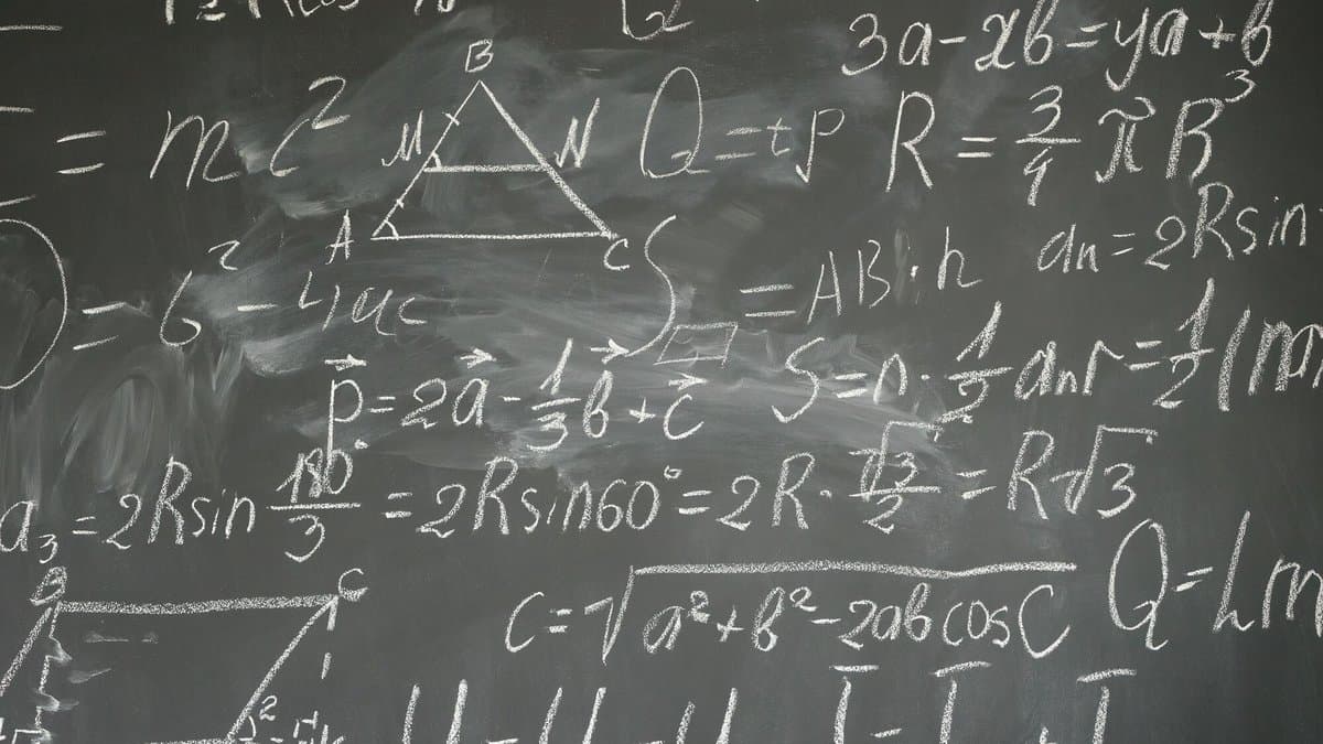A blackboard densely covered with handwritten mathematical formulas and a labelled triangle, in white chalk.