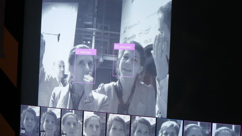 A display showing two faces on a video feed, each ringed by a pink face-detection box labelled ‘Unknown’, with a row of cropped face thumbnails beneath.