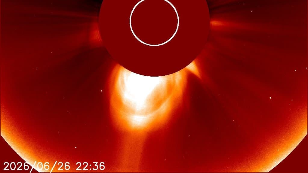 Coronagraph image of the Sun, its disk hidden behind a dark occulting disk, with a bright loop-shaped cloud of solar plasma expanding away below it; the date and time 2026/06/26 22:36 are stamped in the lower left corner.