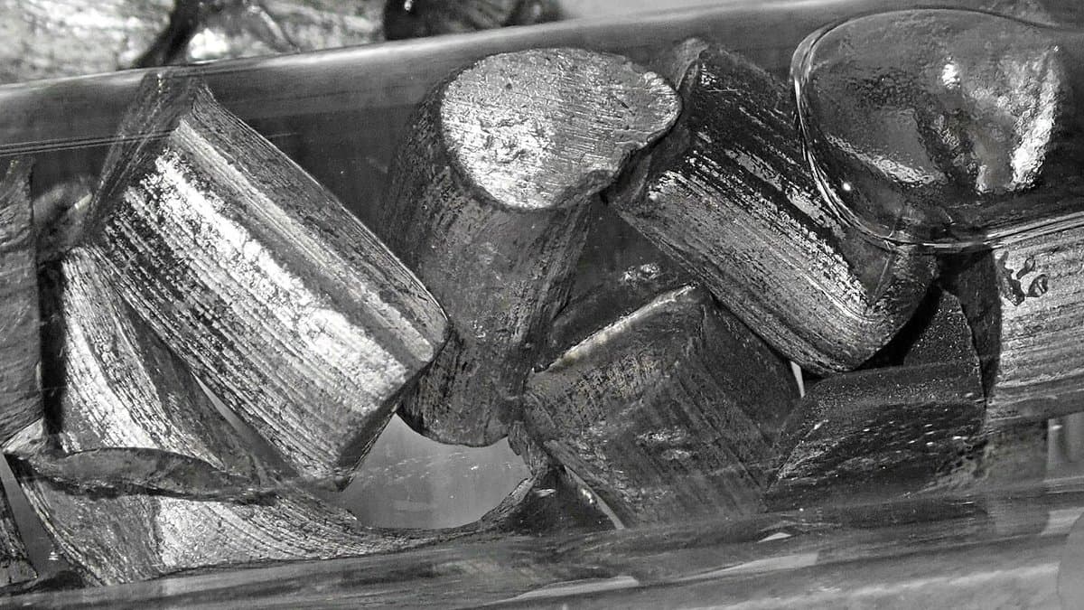 Cut chunks of silvery lithium metal with bright, striated freshly exposed surfaces, stored under oil.