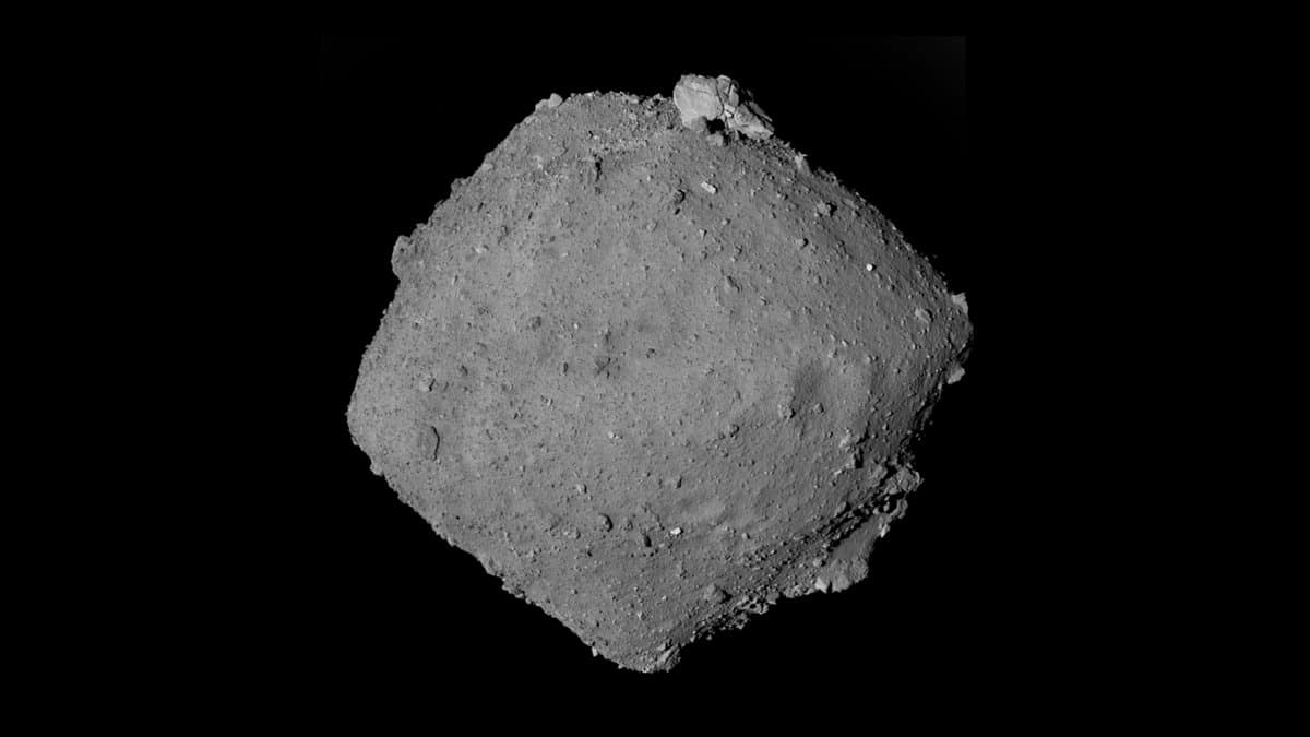 A grey, diamond-shaped rubble-pile asteroid photographed against black space, its surface covered in boulders and a ridge running round its equator.
