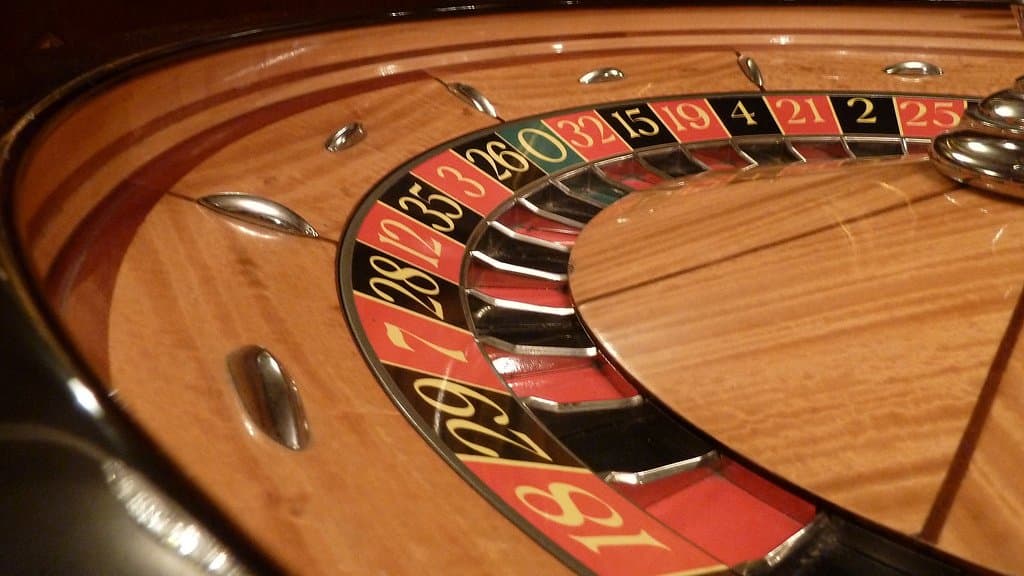 Close-up of a polished wooden gaming wheel, its numbered red and black pockets curving away from the camera.