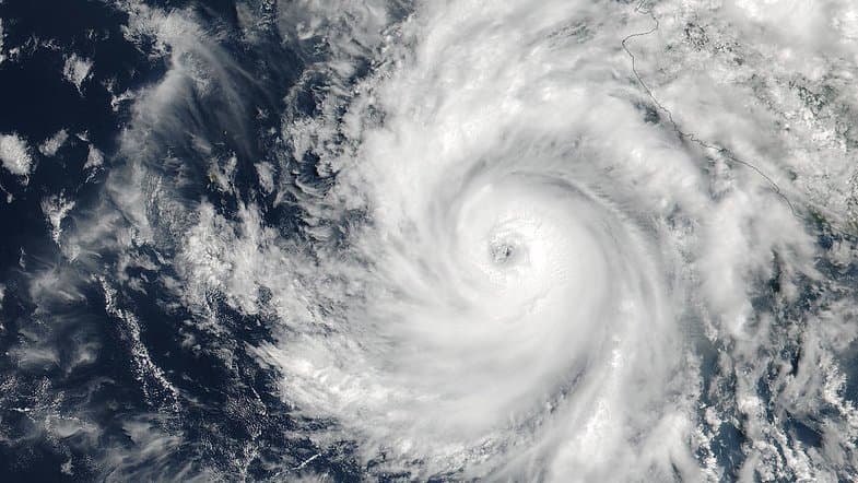 Satellite view of a large hurricane over dark blue ocean, its spiral cloud bands wrapped around a small clear eye.