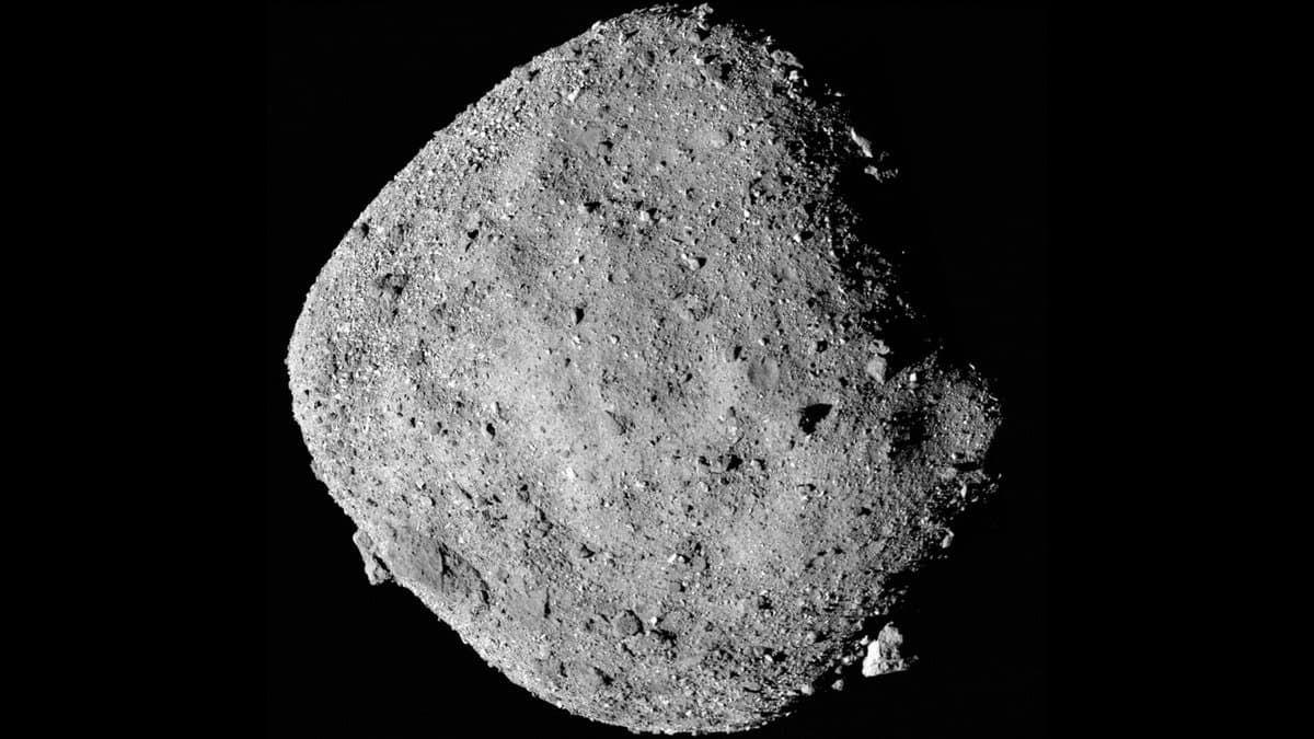 The near-Earth asteroid Bennu, a rounded spinning-top shaped body covered in boulders, imaged in grey tones against black space.