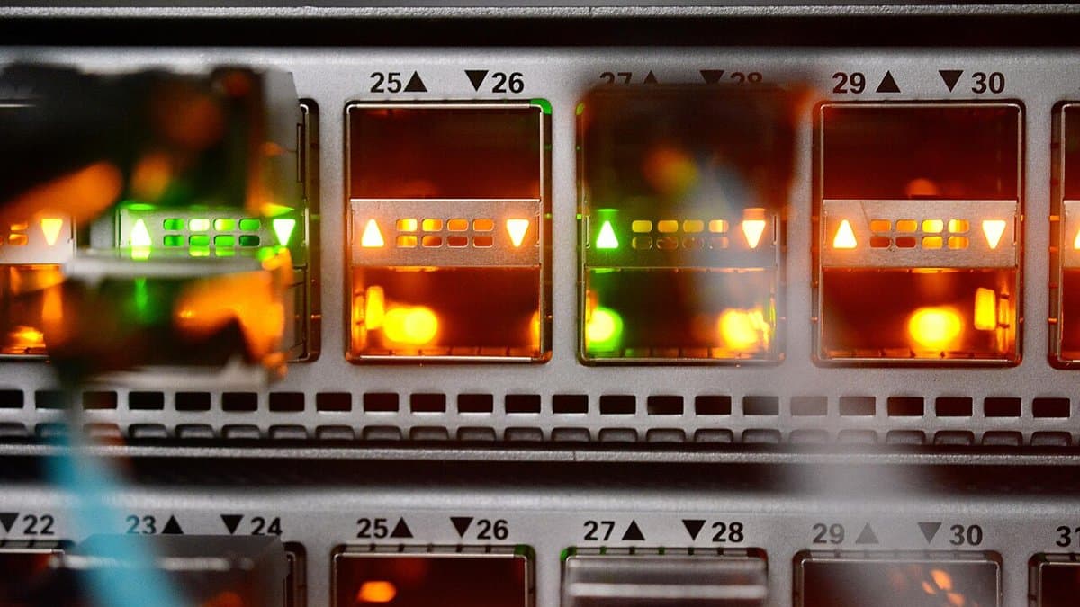 Close-up of illuminated network switch ports in a high-performance computing centre, with numbered port bays glowing orange and green.