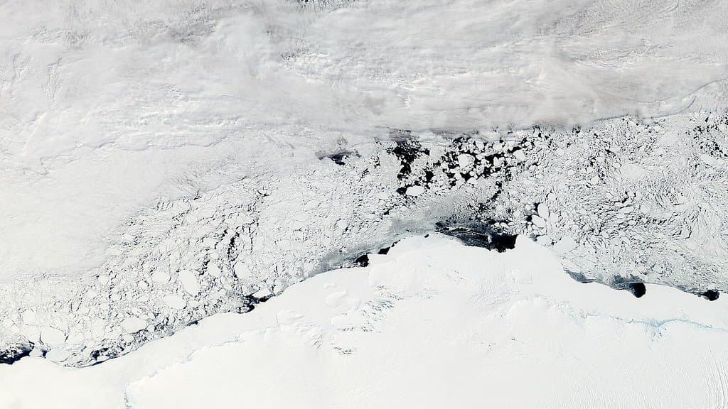 Satellite view of the Enderby Land coast in East Antarctica: the white ice sheet along the bottom, broken sea ice offshore and bands of cloud over the ocean beyond.