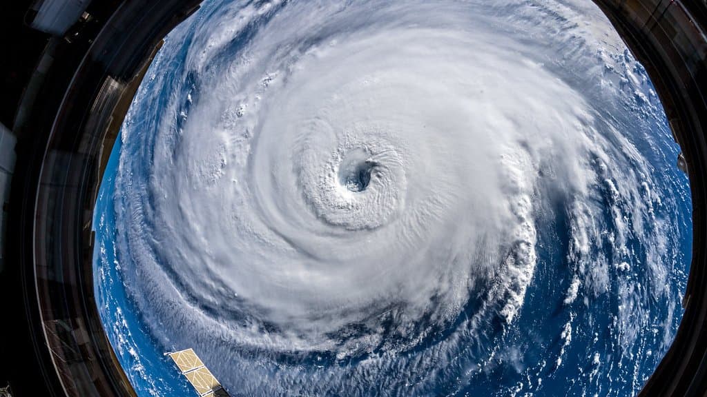 The eye of Hurricane Florence seen from the International Space Station, a vast white spiral of cloud over dark blue ocean, framed by the station's cupola window.