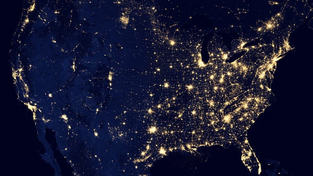Nighttime satellite image showing the glowing lights of cities and urban corridors