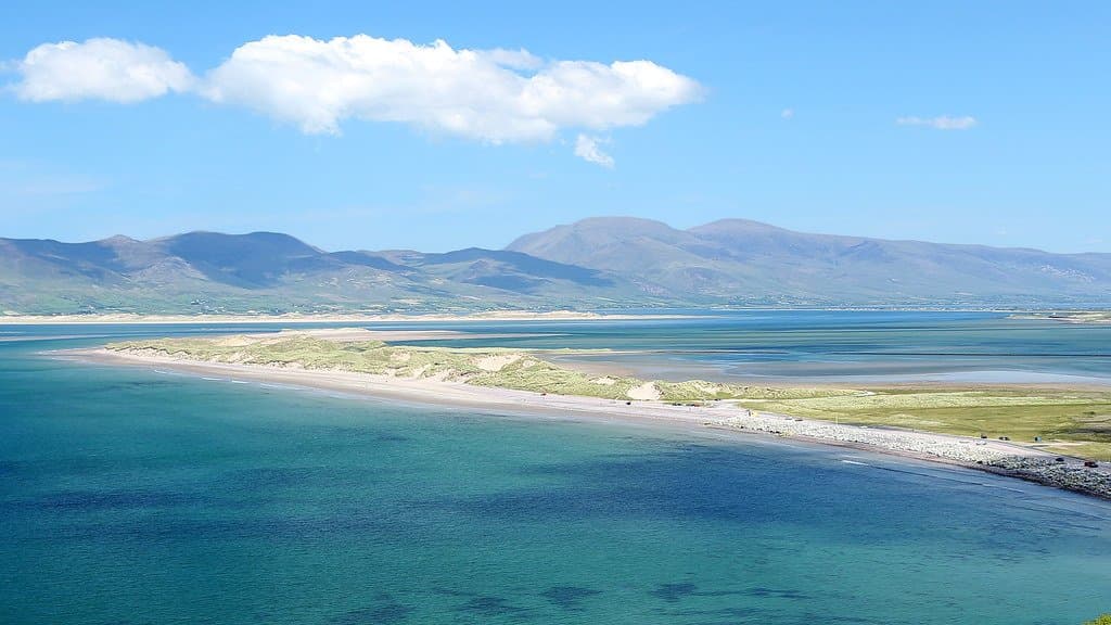Aerial view of a long sand and dune spit reaching into Dingle Bay on Ireland's Atlantic coast, with mountains behind
