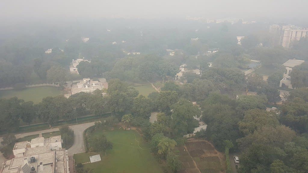 Aerial view of central New Delhi, where buildings, roads and trees fade into thick gray haze.