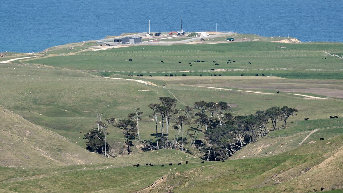A green coastal headland above the sea, with the low buildings and launch tower of Rocket Lab's Launch Complex 1 standing on the point.