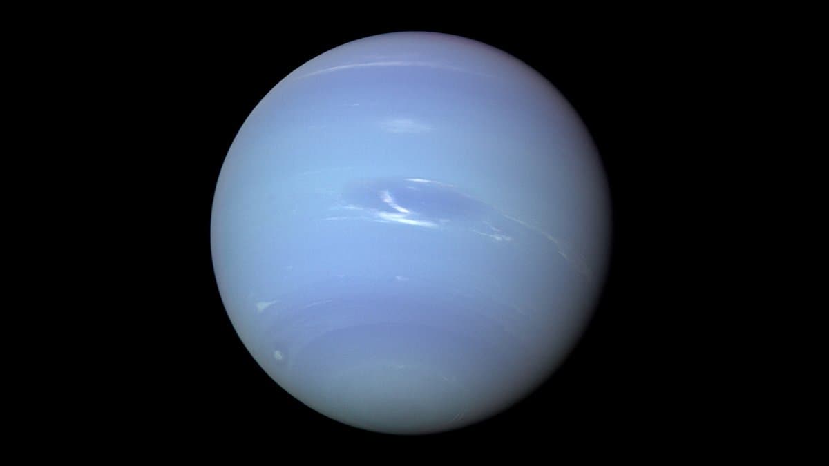 The full disk of Neptune, a pale blue planet with faint white cloud bands and a dark oval storm, against black space.