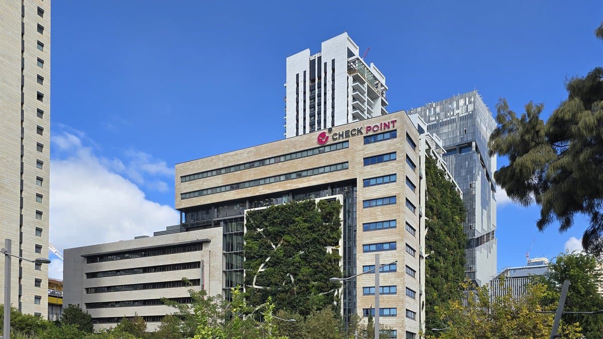 A stone and glass office tower in Tel Aviv with a Check Point logo sign along its roofline, seen from a park on a clear day.