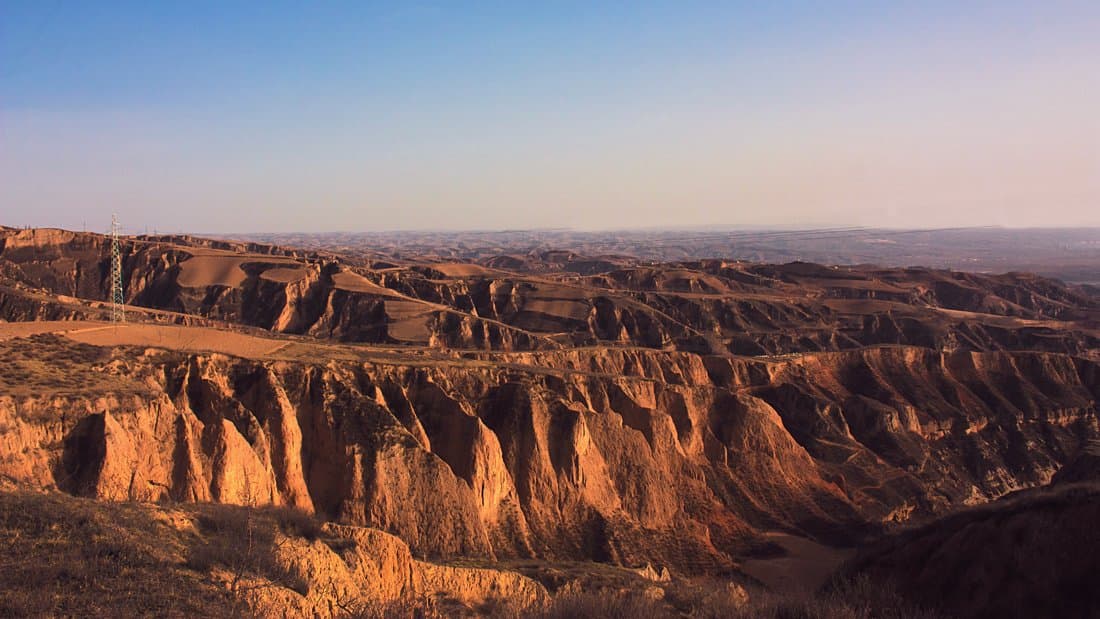 Gullies and terraces cut into thick wind-blown dust deposits on the Chinese Loess Plateau, lit by low sun.