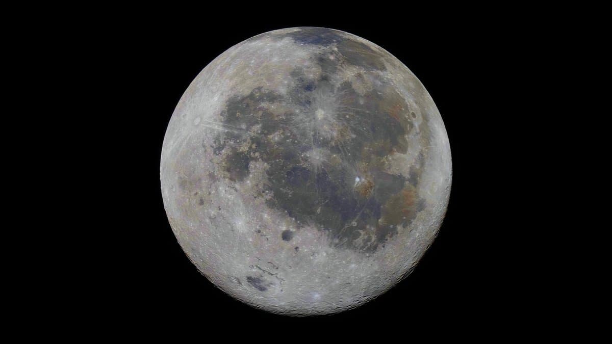 The full Moon against a black sky, gray highlands and darker maria spread across the disk, with faint color differences over the surface.