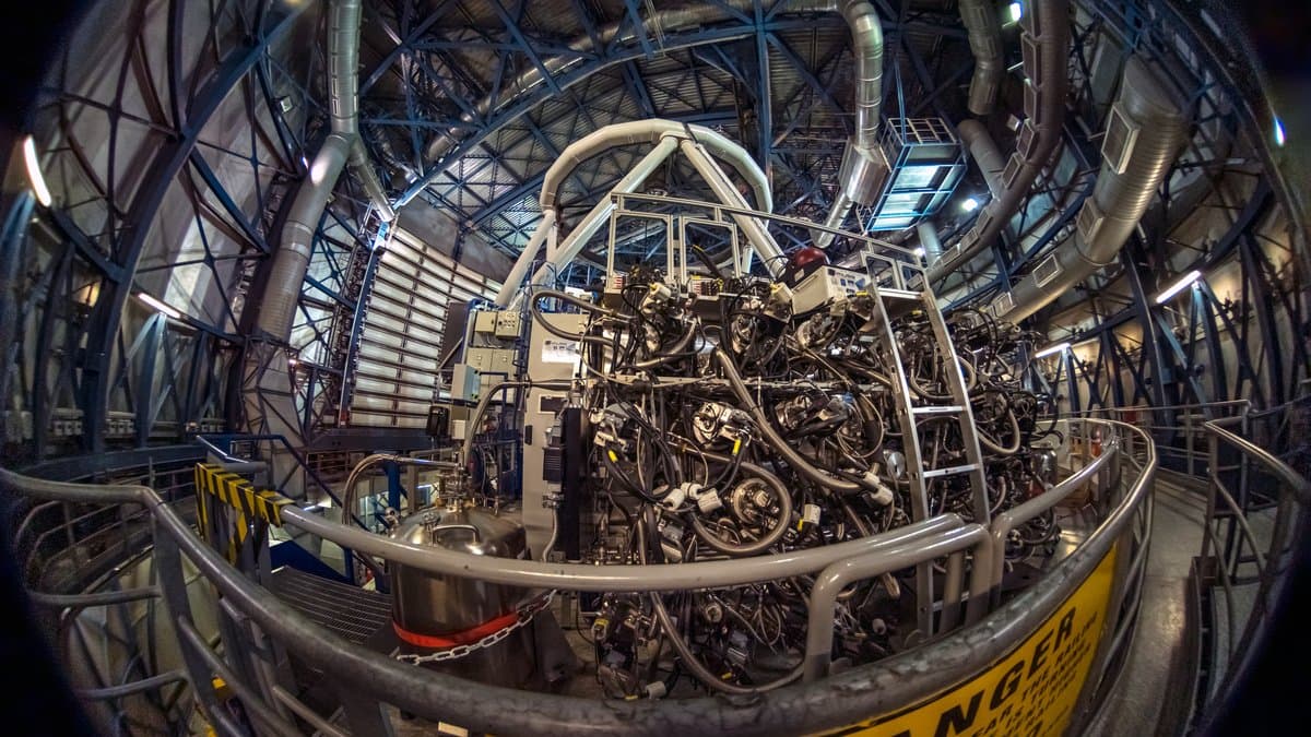 Fisheye view inside a telescope dome, with the MUSE instrument, a large assembly wrapped in cabling and optical units, mounted on the Very Large Telescope's Unit Telescope 4.