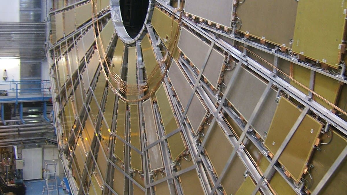 An end-cap wheel of muon detector chambers on the ATLAS experiment, with radial gold-colored panels around a central beam opening, during assembly in the underground cavern at CERN.