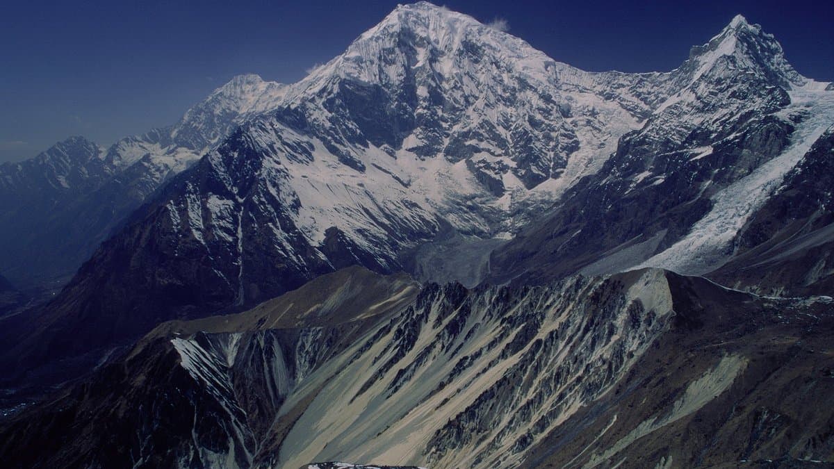 Snow and ice on the steep face of Langtang Lirung in Nepal, with a debris-covered glacier and moraine ridges in the valley below