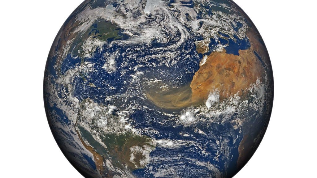 Full-disk satellite view of Earth centered on the Atlantic, with a tan plume of Saharan dust streaming west from North Africa across the tropical ocean.