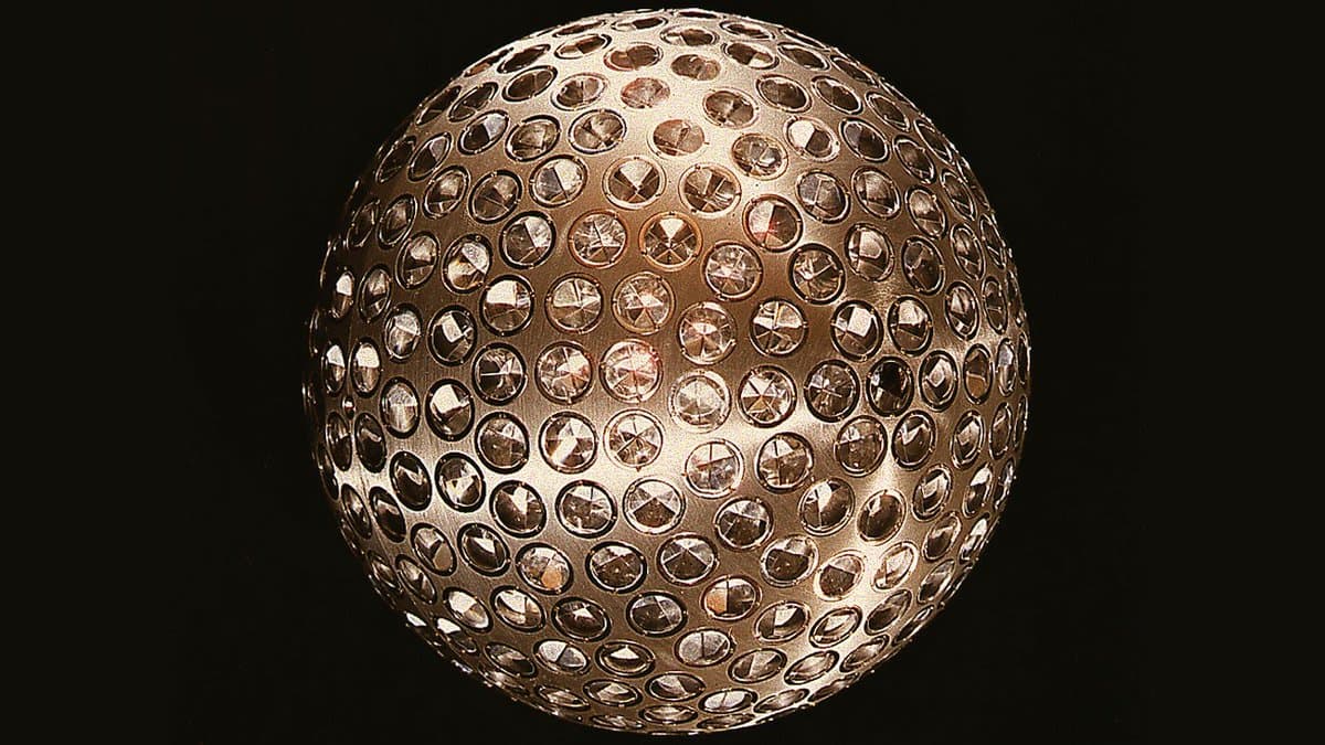 A metal sphere studded with hundreds of round corner cube reflectors, photographed against a black background.