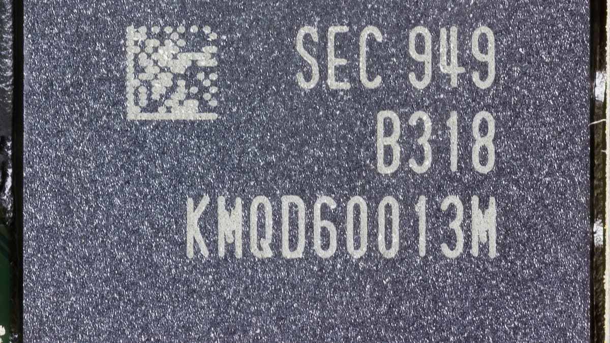 Close-up of a black Samsung mobile memory package soldered to a green smartphone circuit board, its laser-etched part number visible on the lid.