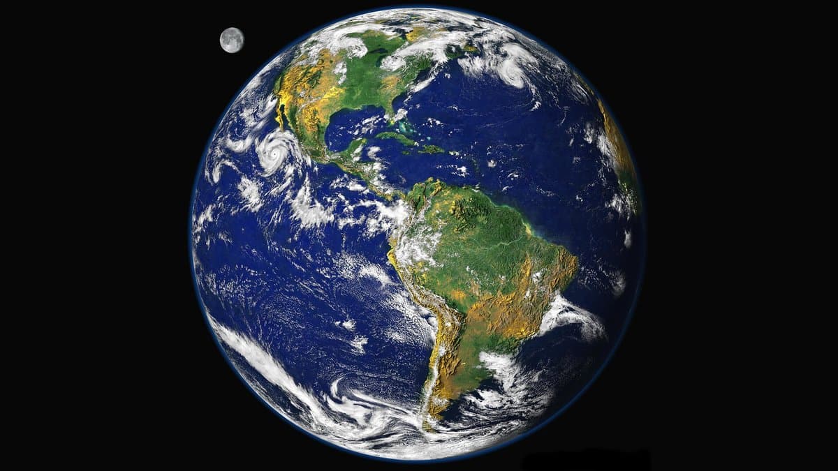 A full view of Earth over the Americas assembled from satellite observations of land, ocean, sea ice and clouds, with the Moon at upper left.