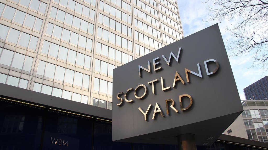 The revolving New Scotland Yard sign standing outside a glass-fronted office tower in London.