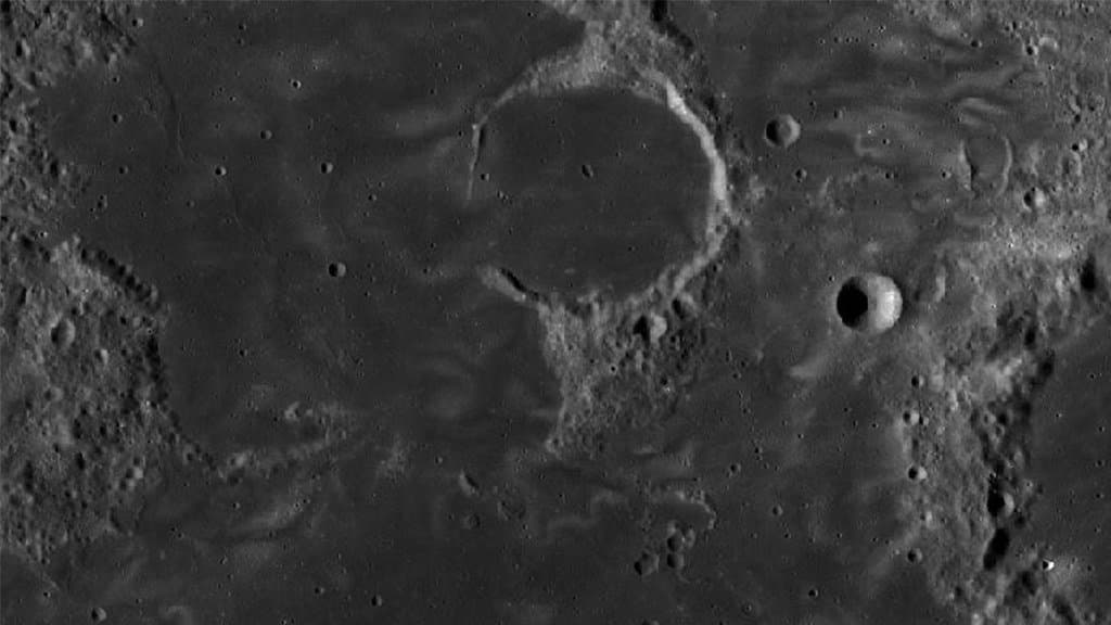 Bright, winding lunar swirl markings crossing a cratered lunar surface in an orbital image.