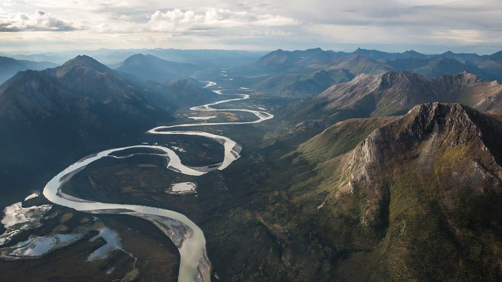Aerial view of a braided river winding between mountains and tundra in the Brooks Range of northern Alaska.