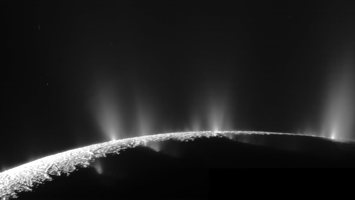Narrow jets of icy particles rise from the shadowed south polar limb of Saturn's moon Enceladus, backlit against black space.