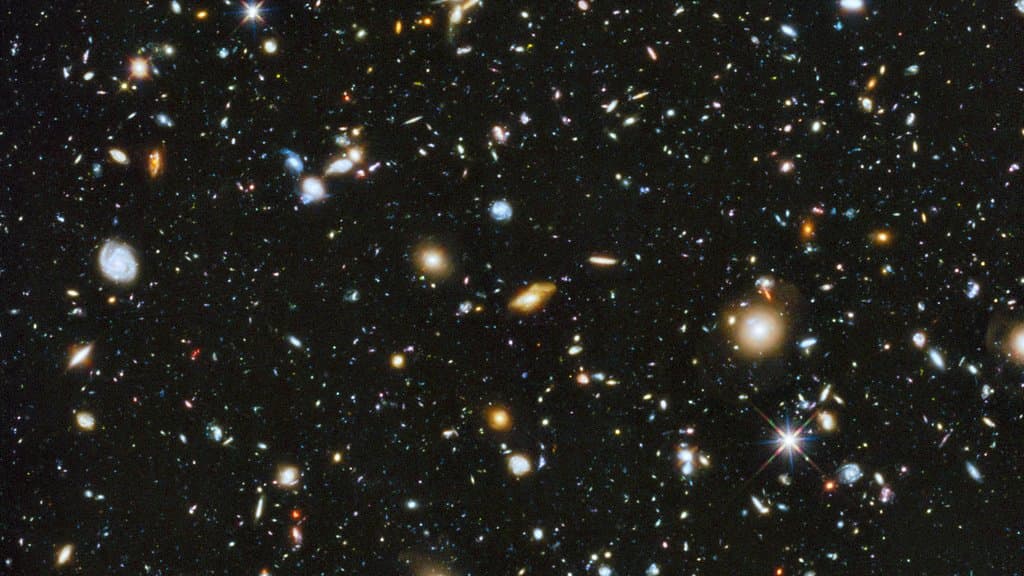 A small patch of sky crowded with thousands of galaxies of many shapes and colors against black space, the Hubble Ultra Deep Field.