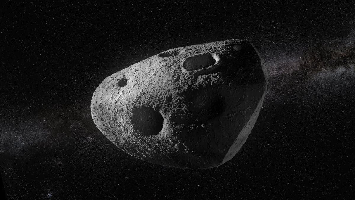A visualization of a gray, heavily cratered asteroid lit from the left against a dense starfield.