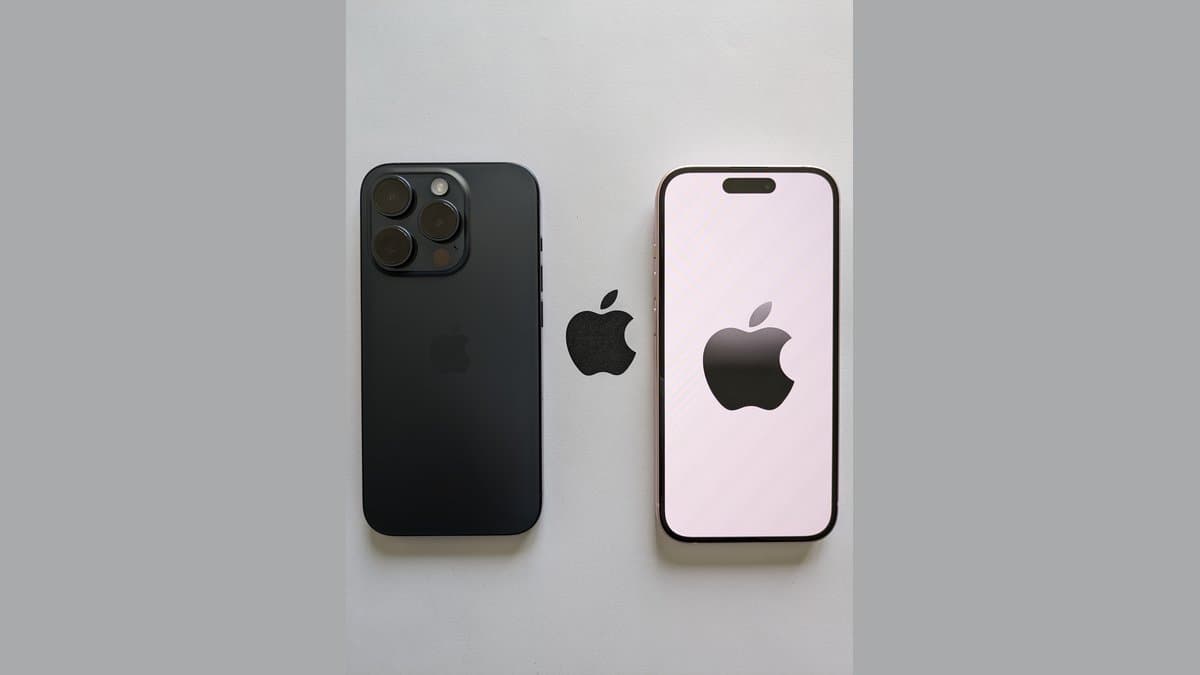Two Apple smartphones lie side by side on a gray surface, one showing its dark back and camera module, the other a lit screen with an Apple logo.