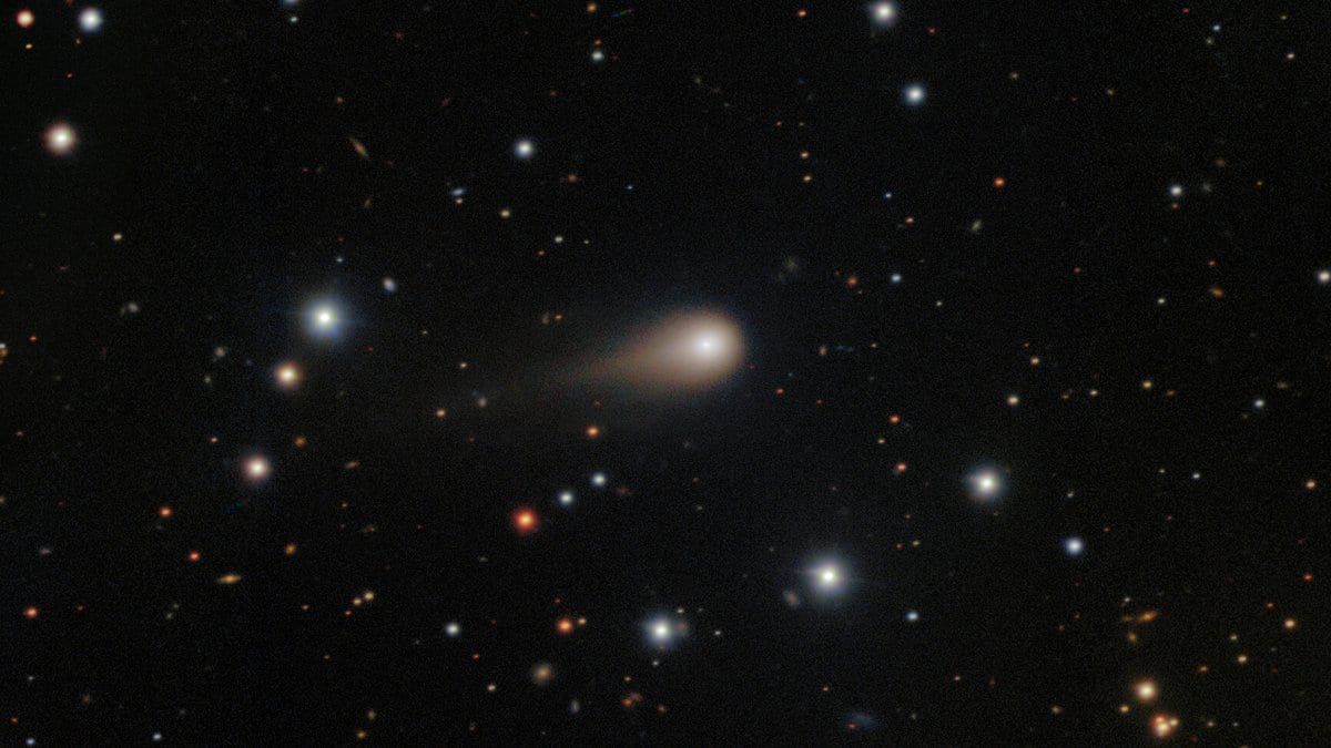 Telescope image of interstellar comet 3I/ATLAS showing a bright coma and a growing dust tail against a starfield