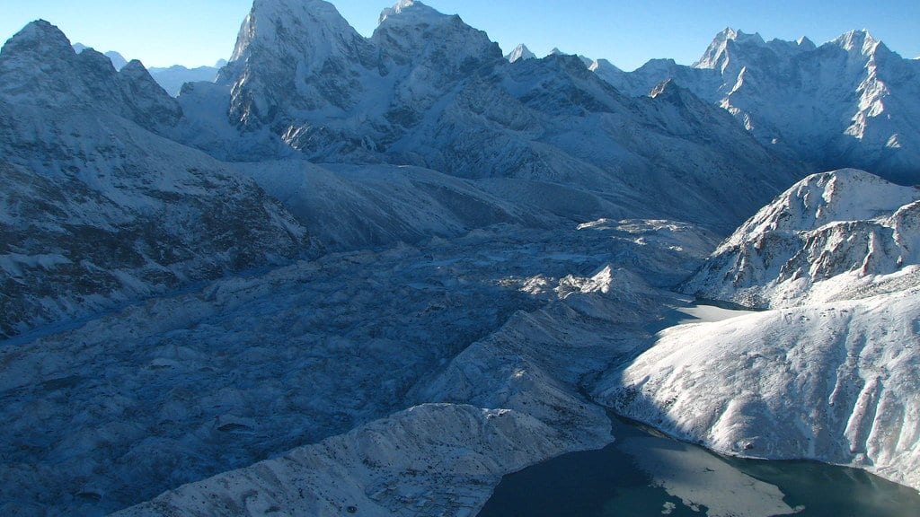 A large Himalayan glacier below snow-capped peaks in Nepal at sunrise