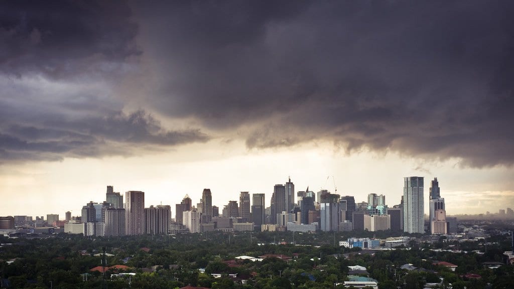 Dark, heavy storm clouds and rain over a East Asian city skyline.