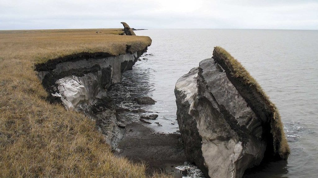 An eroding Arctic coastal bluff of frozen ground collapsing into the sea