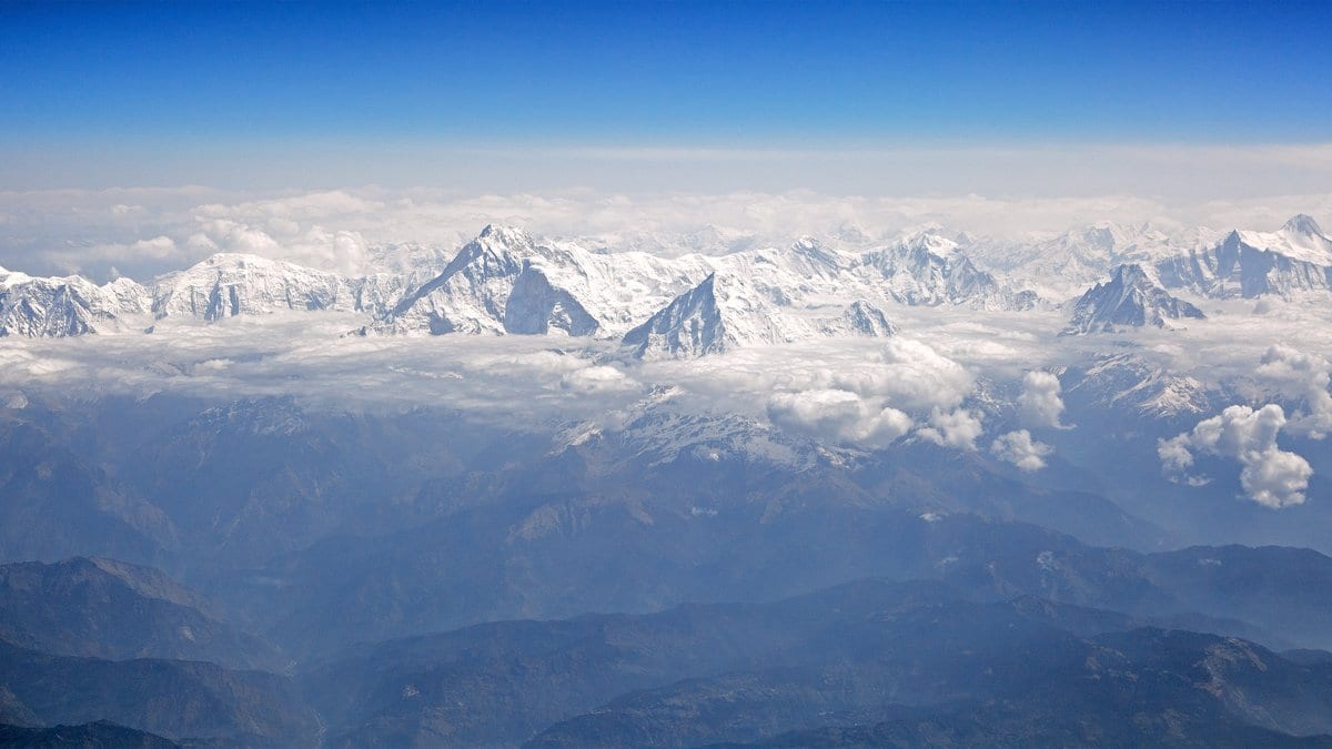 Aerial view of the snow-covered Annapurna massif in the Nepal Himalaya, glaciated peaks and steep ridges rising above cloud.