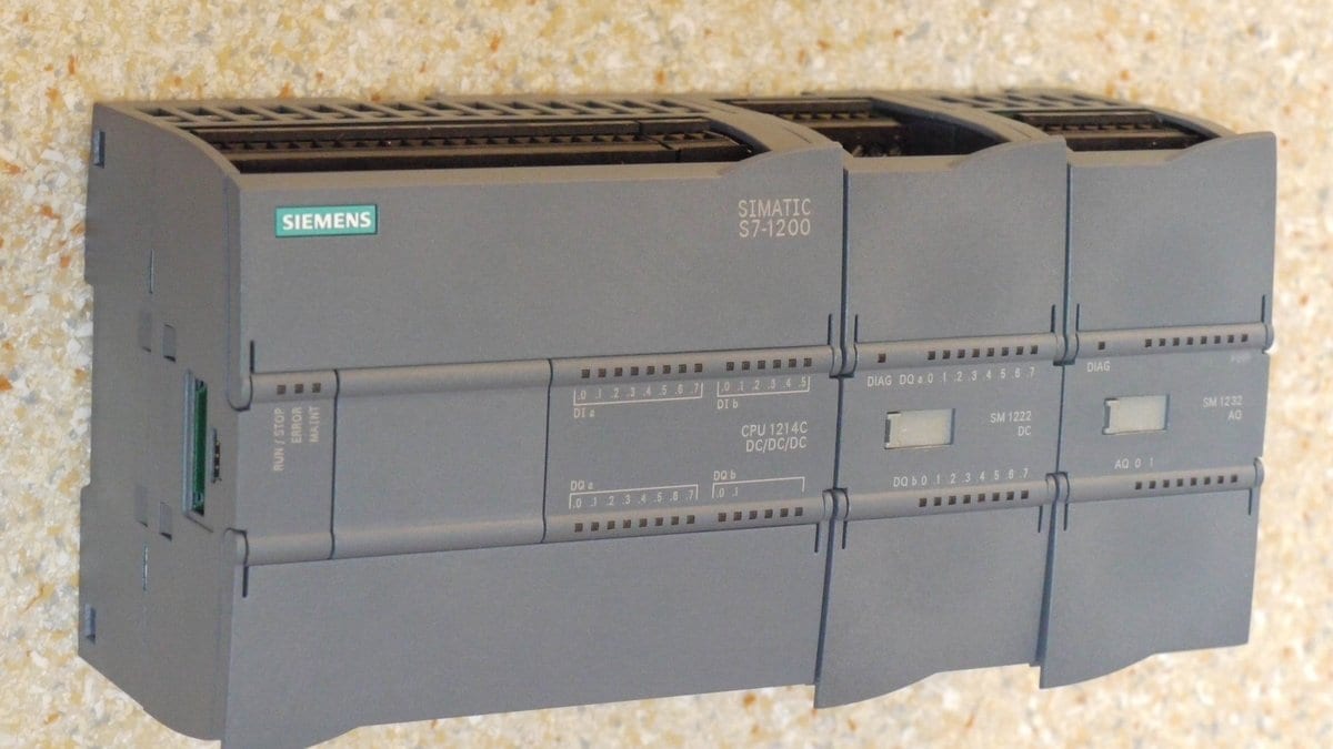A Siemens Simatic S7-1200 programmable logic controller mounted on a DIN rail with wiring terminals and status LEDs