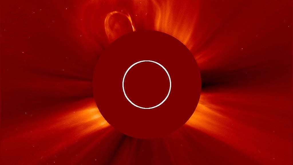 Two coronal mass ejections billow away from the Sun as bright clouds of plasma beyond the dark occulting disc of a coronagraph.